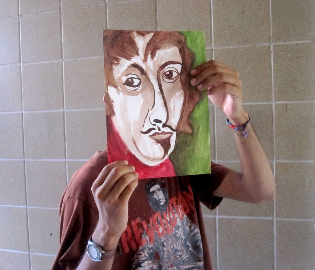 Ropa segurando uma de suas pinturas na frente do rosto